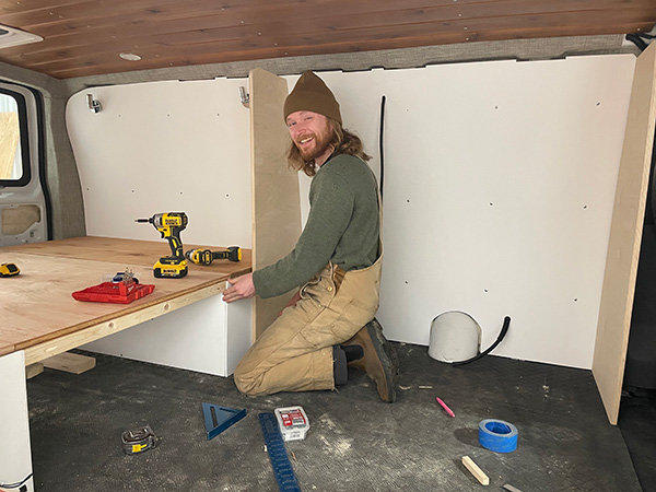 Tyler installing a bed frame in a camper van.